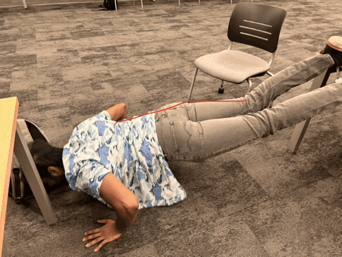 a person doing push ups under a chair with a red line going through their back