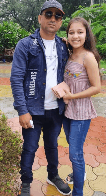 a man and a girl posing for a picture with the man wearing a superior shirt