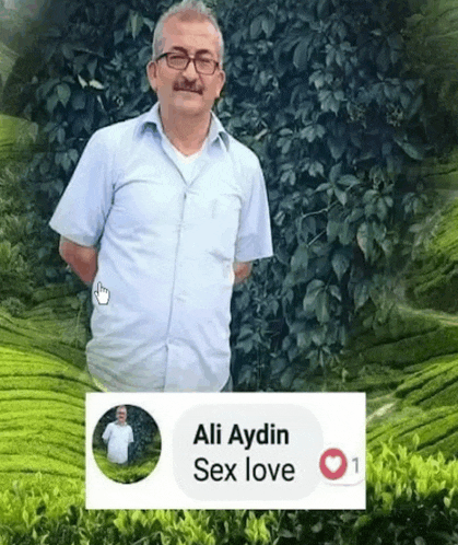 a man with glasses and a mustache is standing in front of a wall of leaves .