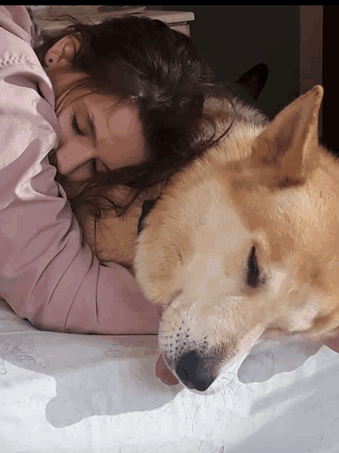 a woman is laying on a bed with a dog