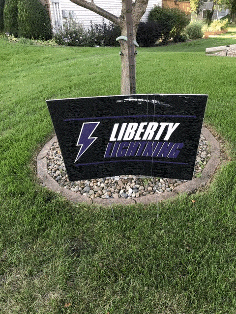 a sign for liberty lightning sits in the grass