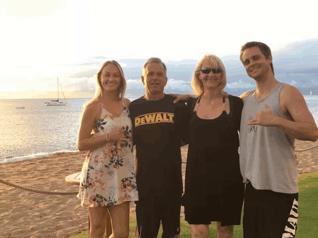 a man in a dewalt shirt poses with his family on the beach