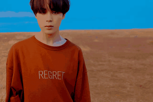 a young man wearing a brown shirt that says regret on it