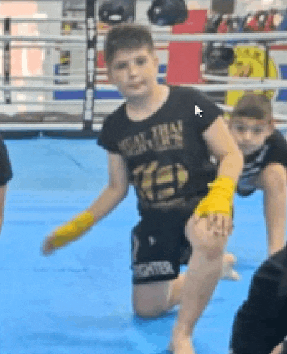 a young boy is kneeling on the floor in a boxing ring .