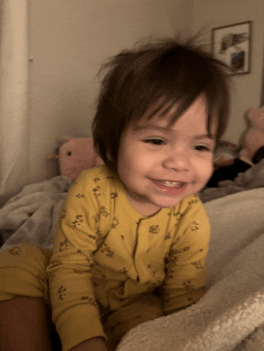 a little girl wearing a yellow pajama top smiles for the camera