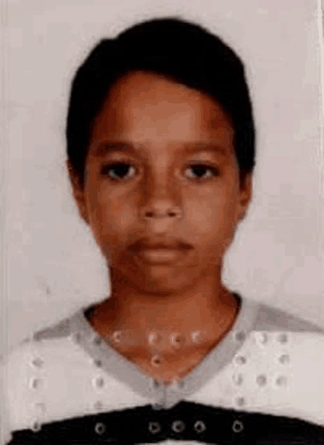 a young boy is wearing a black and white striped shirt and a black belt .