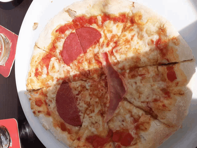 a white plate topped with a pizza with a pepperoni slice on it