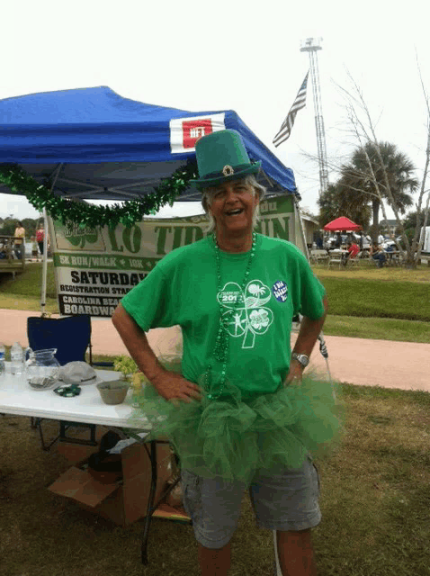 a man wearing a green shirt with a shamrock on it stands in front of a sign that says saturday