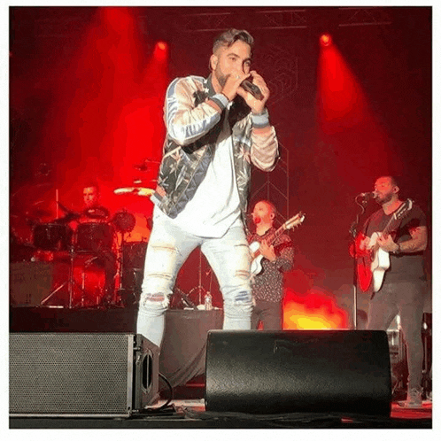 a man is singing into a microphone on a stage with a band .