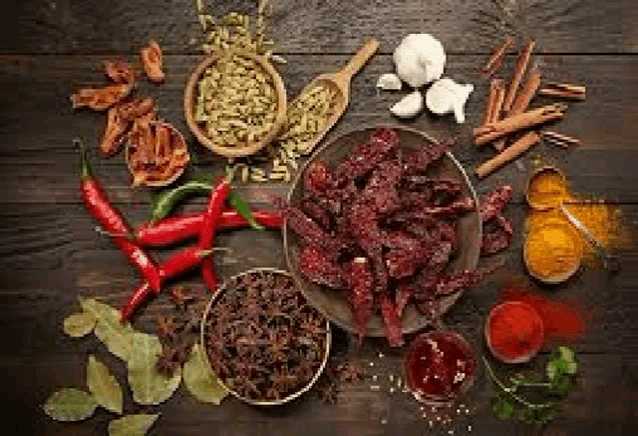 a wooden table topped with a bowl of beef jerky surrounded by spices and herbs .