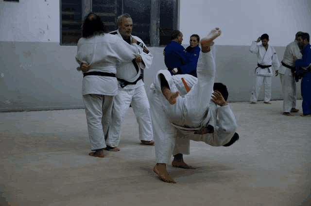 a group of men are practicing judo in a gym with one man wearing a black belt that says ' aoi '