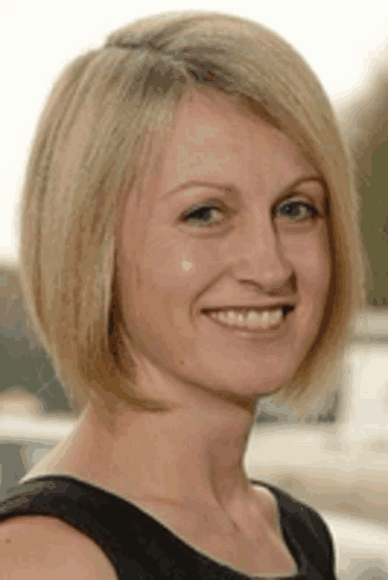 a woman with short blonde hair is smiling for the camera .