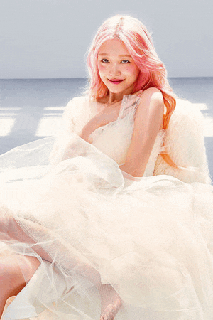 a woman with pink hair and a white dress is sitting on a chair