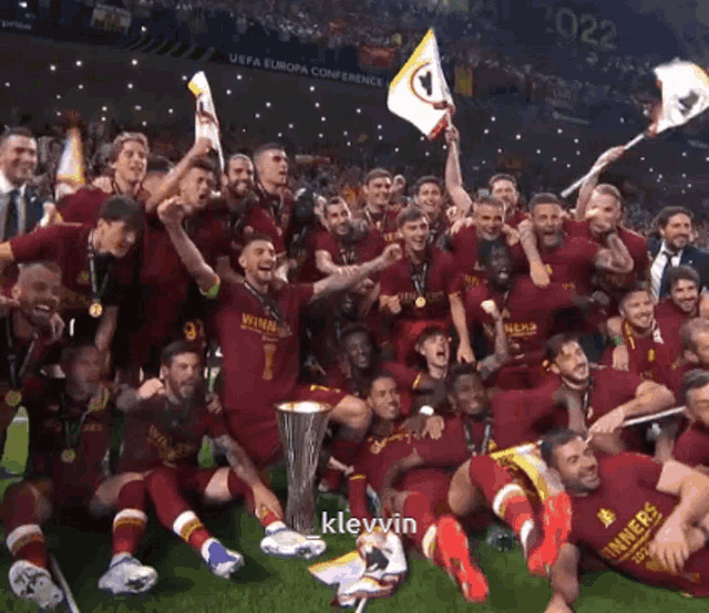 a group of soccer players are posing with a trophy and a flag and the word klevvin is on the bottom