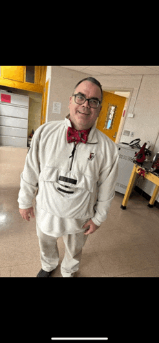 a man wearing glasses and a bow tie is standing in a room