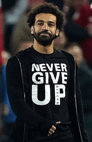 a man with a beard wears a black shirt that says never give up