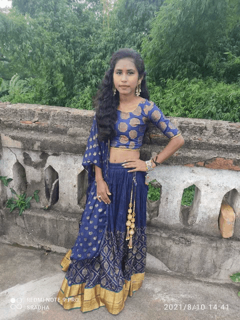 a woman in a blue and gold dress is standing on a bridge with a redmi note 9 pro in the background