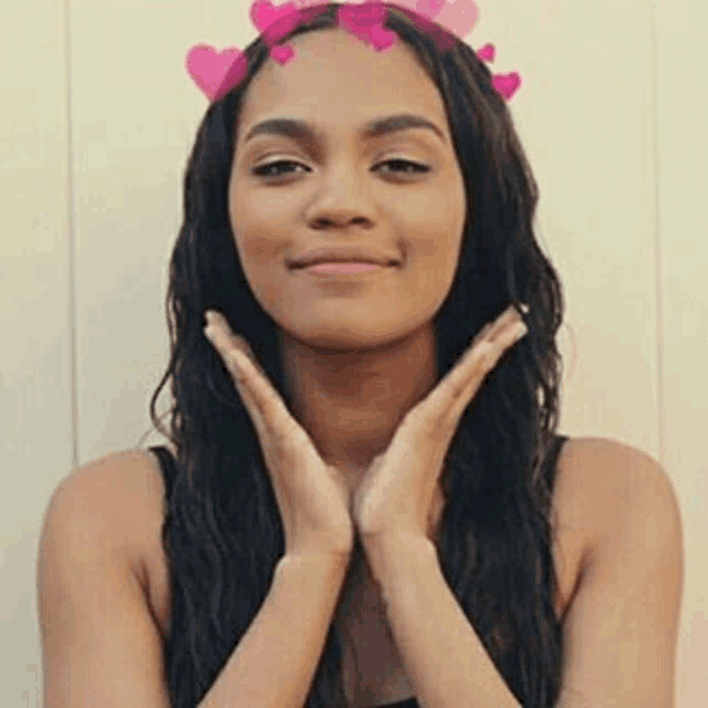 a woman wearing a crown of pink hearts on her head is smiling .