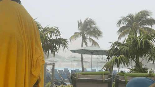 a swimming pool with umbrellas and chairs in the rain