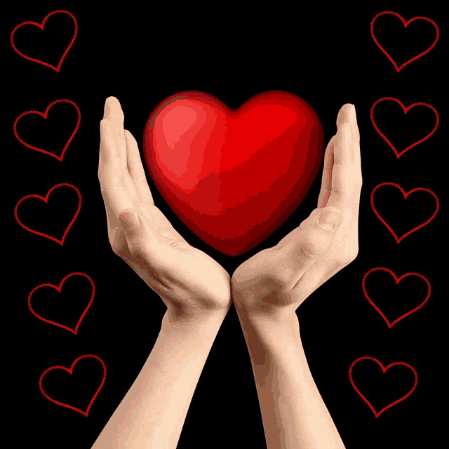 a person holding a red heart in their hands