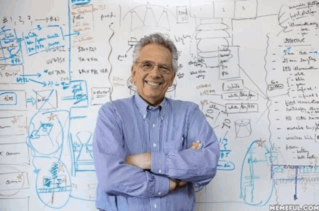 a man is standing in front of a whiteboard with a lot of writing on it