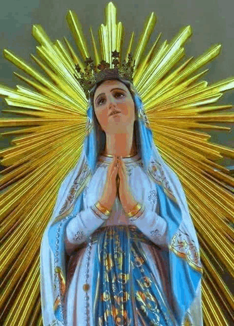 a statue of the virgin mary with a crown on her head is surrounded by rays of light .