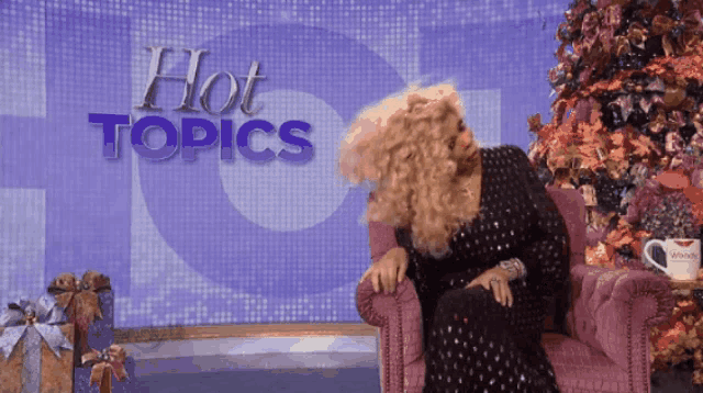 a woman is sitting in a chair in front of a hot topics sign