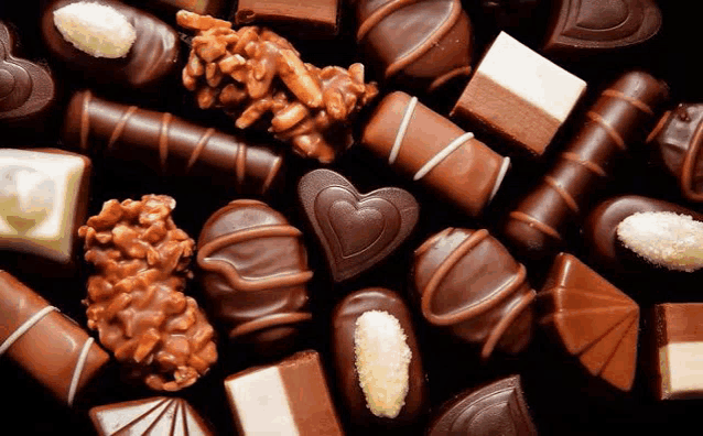 a variety of chocolates are sitting on a black surface .