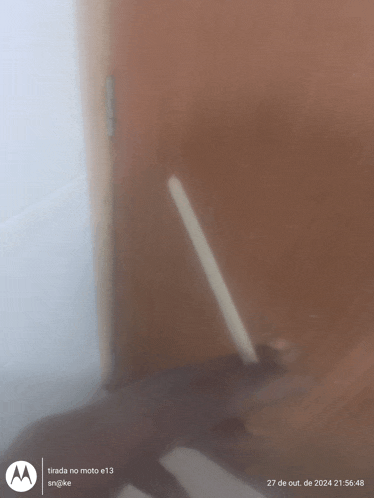 a motorola phone shows a person holding a pencil in front of a brown door