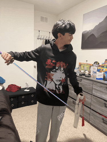 a boy wearing a black hoodie with a girl on it is holding a rainbow ribbon