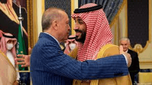 a man in a suit and a man in a keffiyeh are hugging each other .