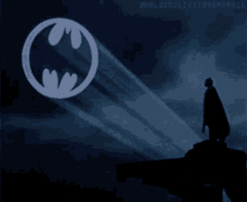 a silhouette of a man standing in front of a batman symbol