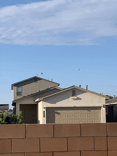 a house with a brick wall in front of it and a blue sky