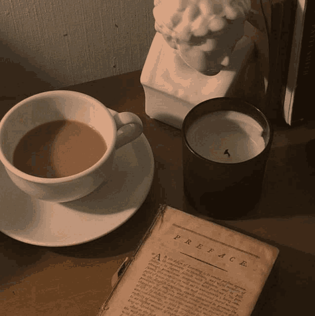 a cup of coffee sits on a saucer next to a book that says preface