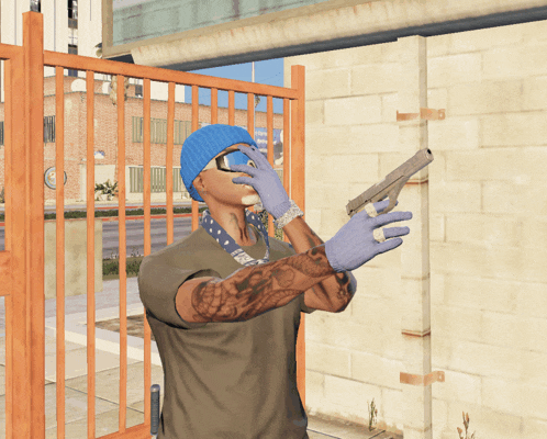 a man wearing a beanie and sunglasses holds a gun in front of a fence