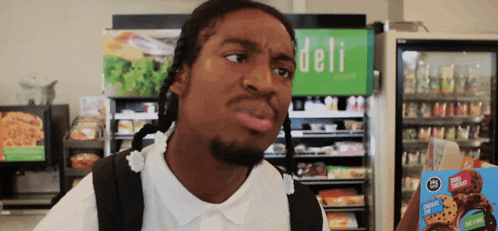 a man in a deli holding a box of cookies