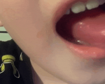 a close up of a child 's mouth with his tongue sticking out .