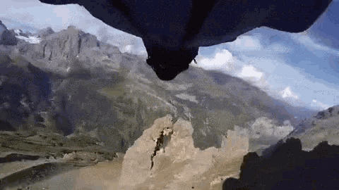 a person is flying through the air over mountains