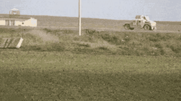 a car is driving down a road next to a field