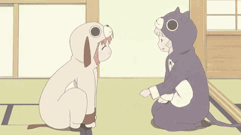 a girl in a dog costume and a girl in a cat costume are sitting next to each other .