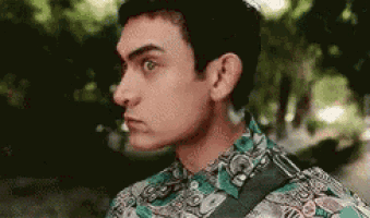 a close up of a man 's face wearing a floral shirt and looking to the side .