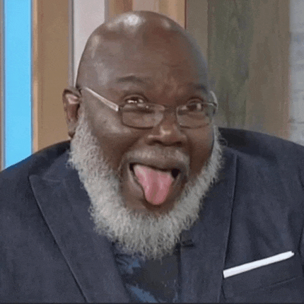 a man with a beard and glasses is sticking out his tongue .