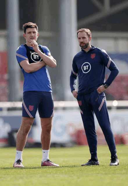 two men standing on a field with one wearing a shirt that says bt on it