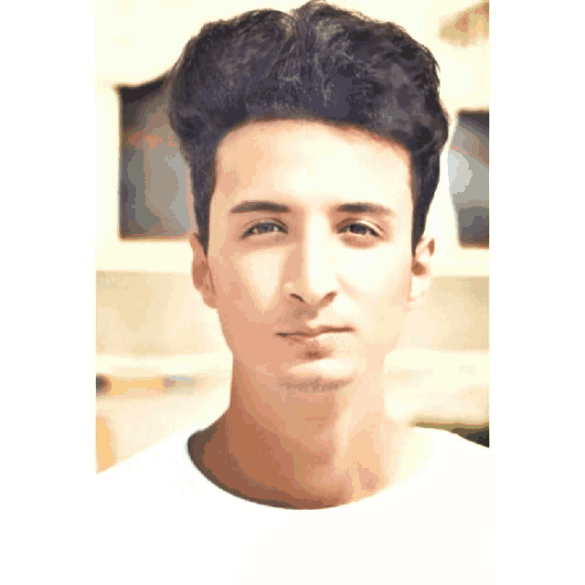 a close up of a young man 's face with a white shirt on