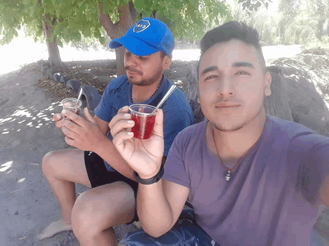 a man wearing a blue cap with the word boca on it sits next to another man