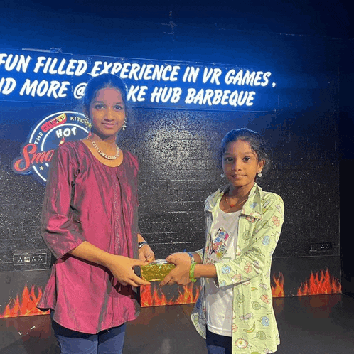 two young girls standing in front of a sign that says fun filled experience in vr games