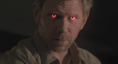 a man with red eyes and a beard looks at the camera