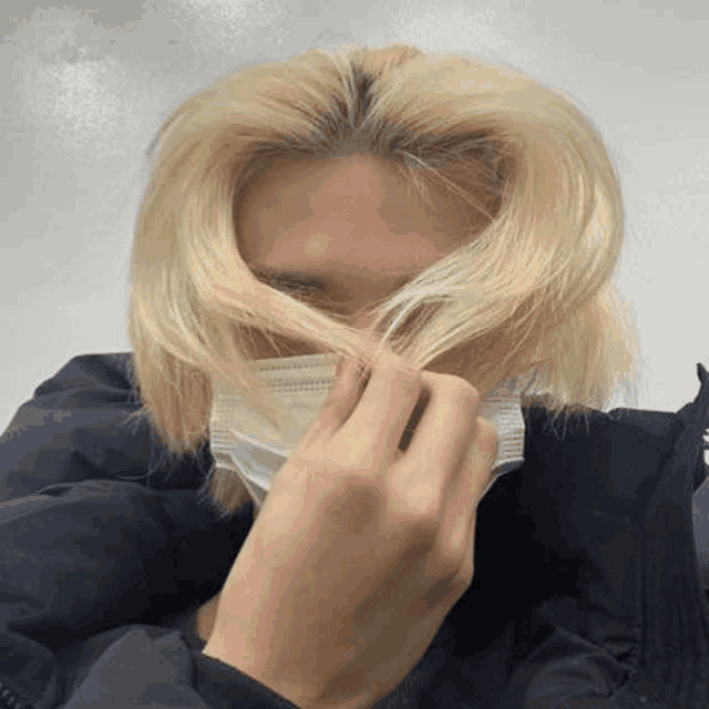 a man with blonde hair is wearing a face mask .