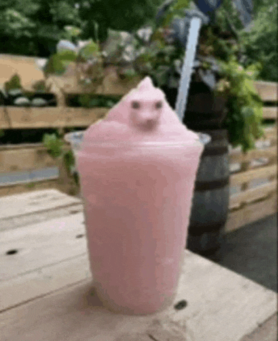 a pink milkshake in a plastic cup with a frog on top of it .