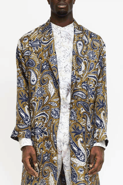 a man is wearing a long paisley jacket